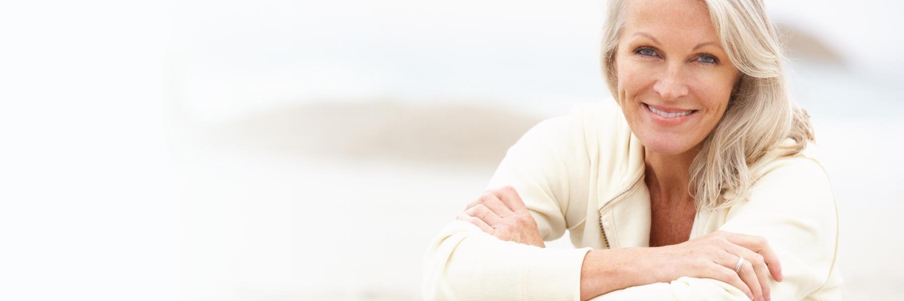 Woman smiling while sitting on rock at beach 